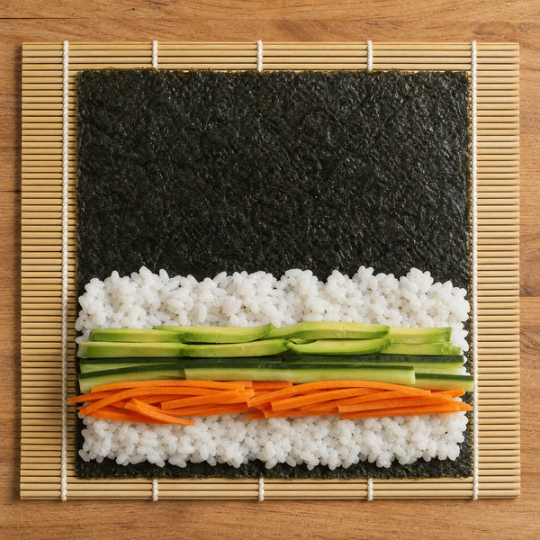 Sushi Nori Blätter mit Reis, Avocado, Gurke und Karotte auf Bambusmatte